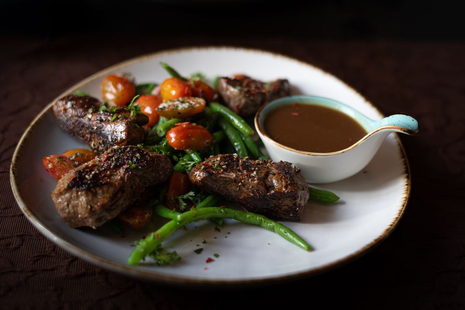 Sumptuous steak and vegetables with a sauce in an elegant setting.