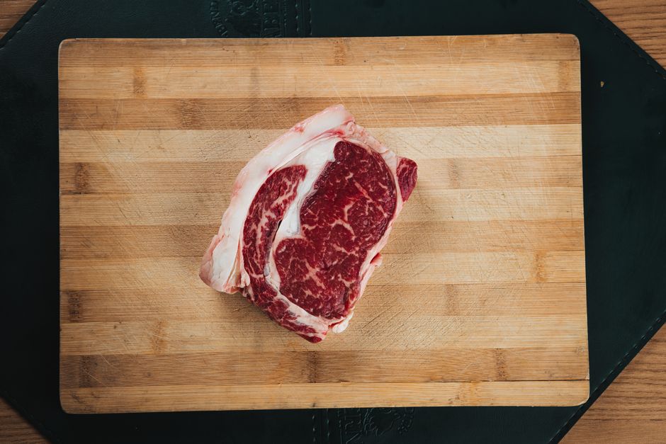Close-up of a marbled ribeye steak on a wooden cutting board, ideal for cooking and food presentations.